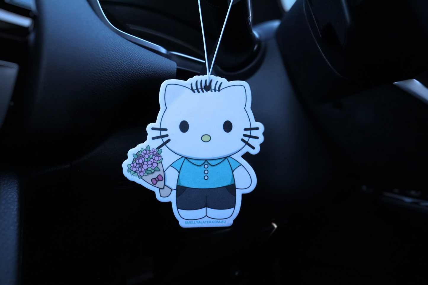 Cute Daniel Starr (Hello Kitty) with blue button shirt, black pants holding pink bouquet of flowers hung in a cool black interior car. Smell Ya Later - Scented Air Freshener. Suitable for homes, wardrobes, cupboards, bathrooms, cars, office space, pet rooms, bed rooms, kitchen.