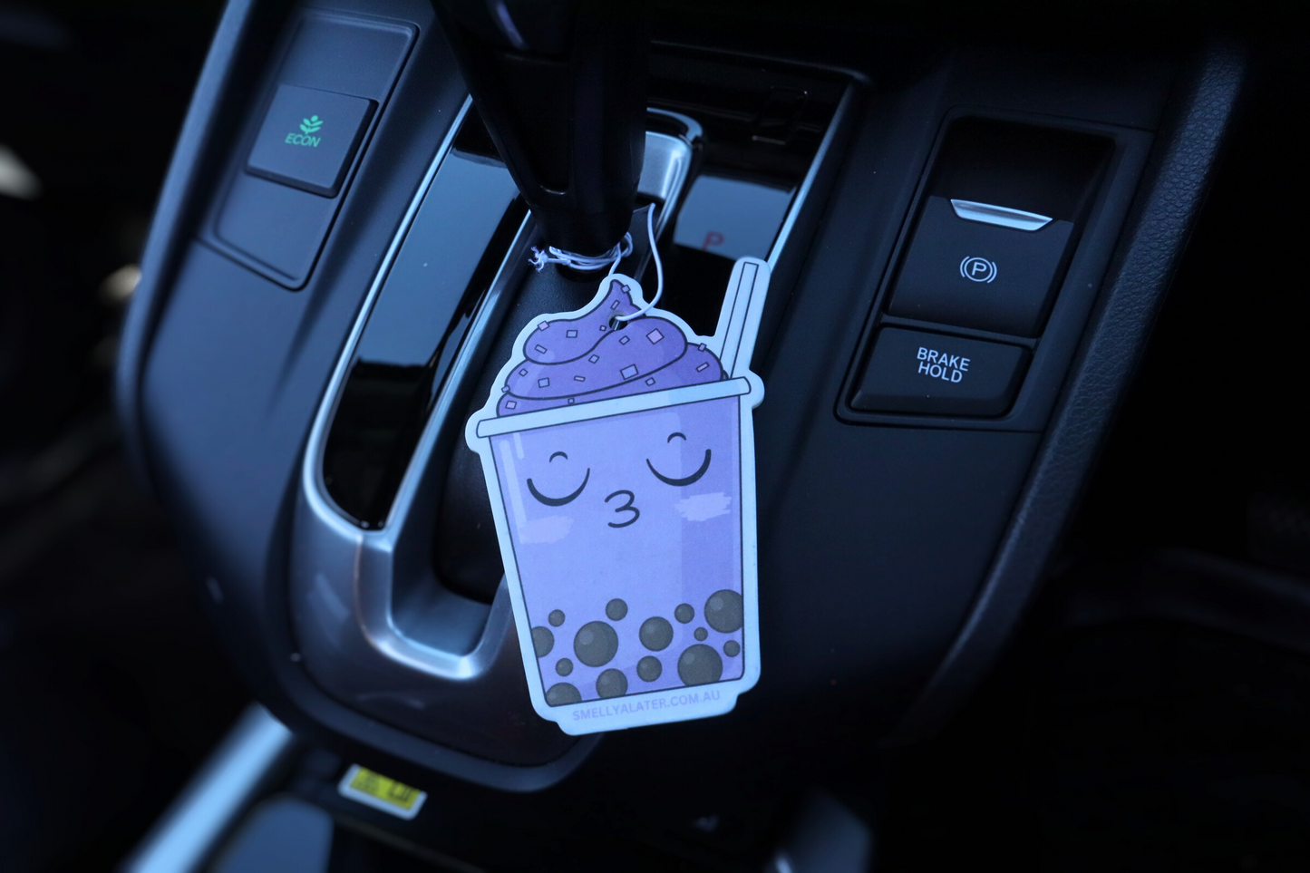 Cute, blushing kissy face purple boba/bubble tea with brown pearls, purple soft serve with sprinkles, hung in a cool black interior car. Smell Ya Later - Scented Air Freshener. Suitable for homes, wardrobes, cupboards, bathrooms, cars, office space, pet rooms, bed rooms, kitchen.